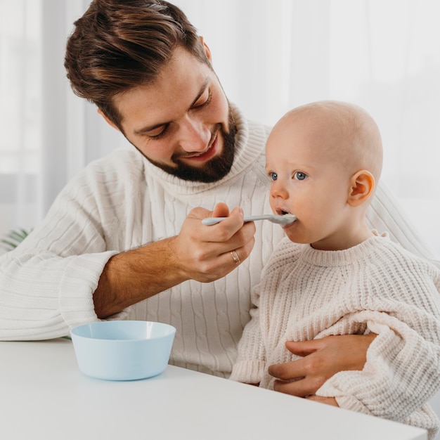 Foto pai feliz alimentando seu bebê