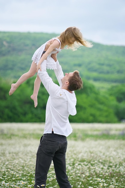 Pai feliz brinca com a filha no campo de camomila