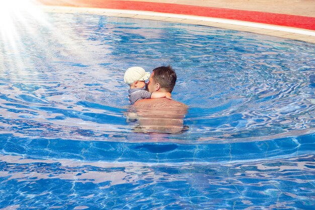 Pai feliz com criança brincando em uma piscina na natureza à beira-mar