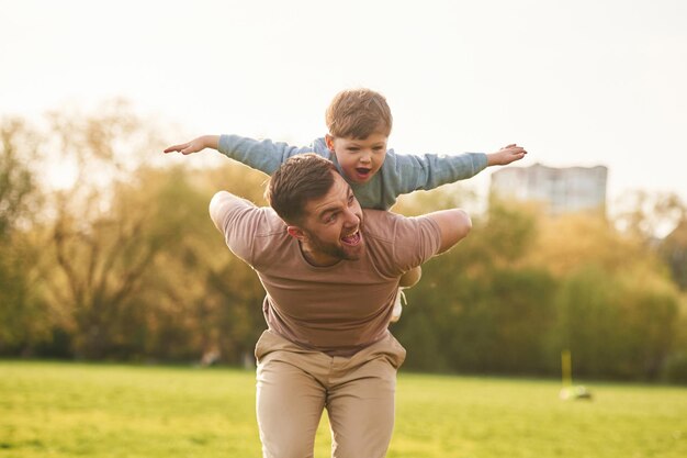 Pai feliz com filho se divertindo no campo no verão