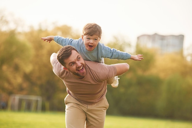 Pai feliz com filho se divertindo no campo no verão