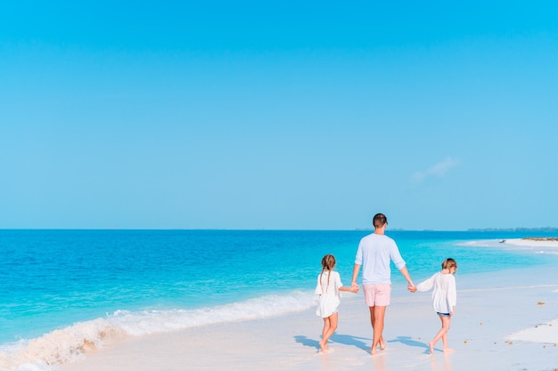 Pai feliz e adoráveis crianças na praia tropical se divertindo. férias com a família