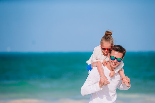Pai feliz e filha na praia de areia branca se divertindo juntos