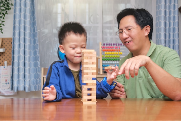 Pai feliz e filho de um menino asiático fofo animado com o jogo de blocos de madeira, pai e filho passando um tempo juntos