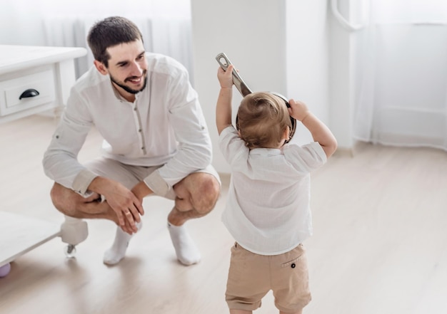 Pai feliz e filho pequeno estão brincando na cozinha O garoto está brincando com uma tigela estilo de vida familiar