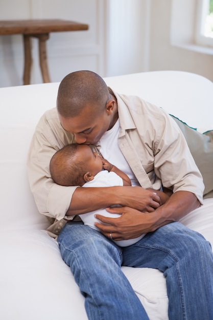 Pai feliz passando o tempo com o bebê no sofá