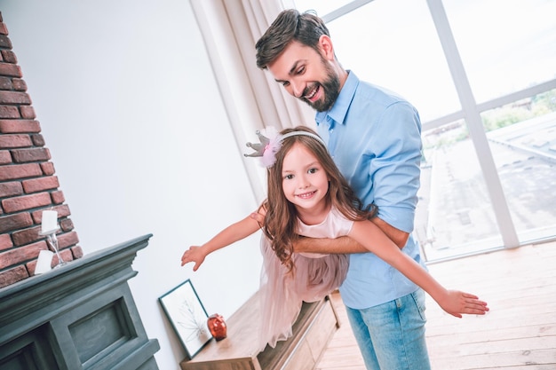 Pai feliz segurando garota nas mãos se divertindo juntos em casa