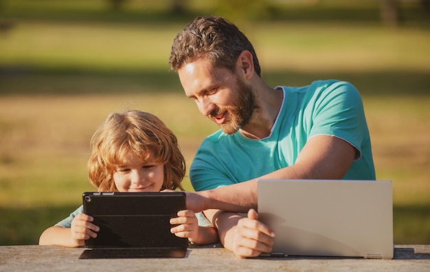 Pai feliz usando laptop relaxa com filho escolar segurando laptop se diverte juntos sorrindo papai e eu