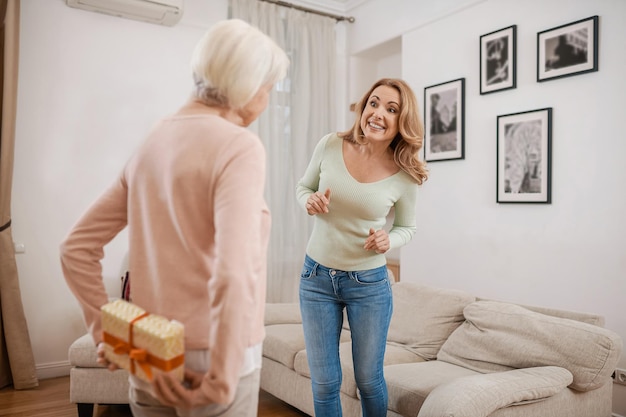 Pai feminino escondendo um presente surpresa para sua filha adulta