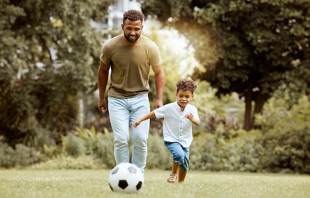 Pai filho e brincando com bola de futebol no parque para um tempo divertido juntos na natureza Pai e filho aproveitando o fim de semana em família ou se exercitando para o verão divertido de futebol lá fora