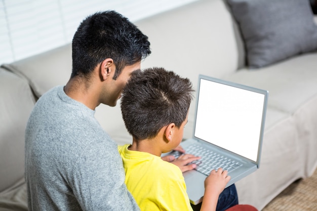 Pai filho, usando computador portátil, sofá