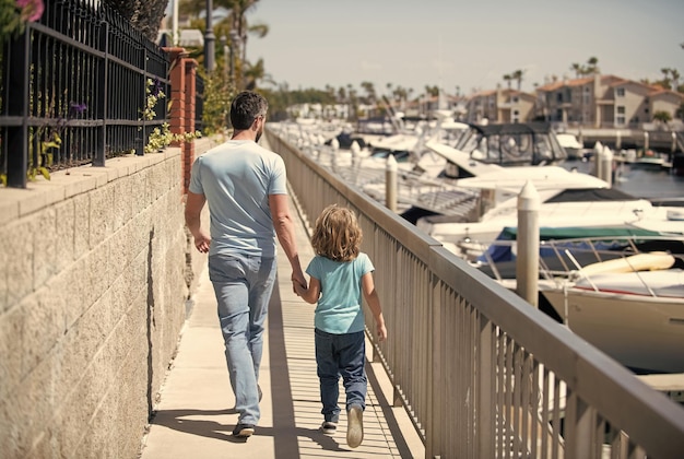Pai homem e menino criança passeio de mãos dadas verão ao ar livre férias em família