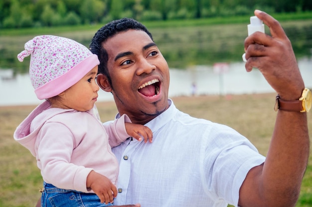 Pai inter-racial transnacional dá ao seu inalador de asma de inalação de menina de raça mista no parque de outono