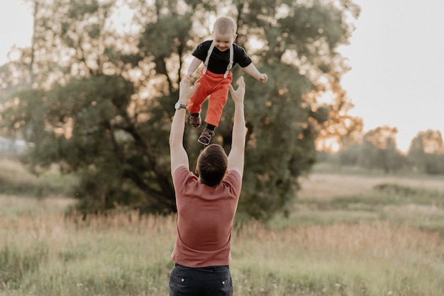 Pai joga um filho feliz em um campo