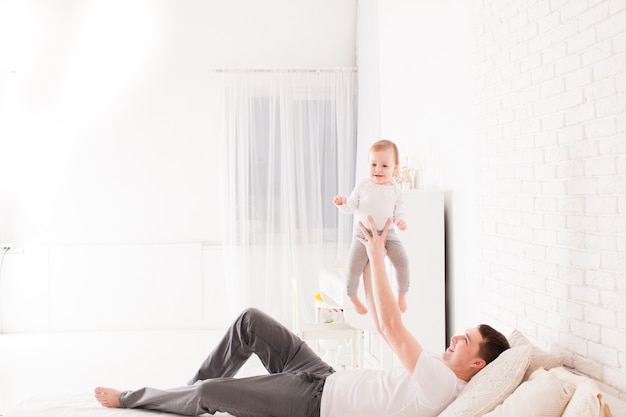 Pai jovem bonito brincando com a filha na cama