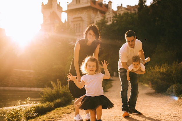 Pai jovem bonito e linda mãe na natureza ensolarada verão brincando com seus filhos pequenos bonitos