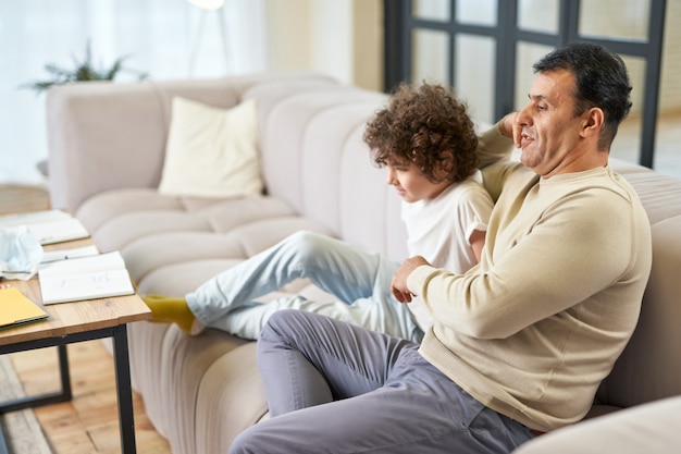Foto pai latino de meia idade feliz passando tempo com seu filho, assistindo tv na sala de estar em casa. família, lazer, conceito de paternidade