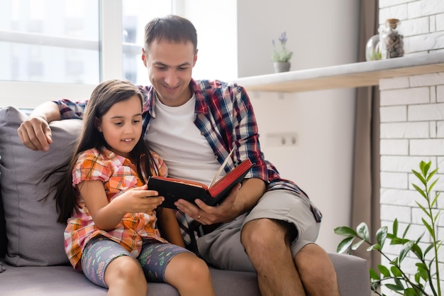 Pai lendo a Bíblia para sua filhinha em casa