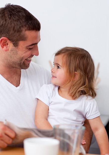 Pai lendo um jornal sorrindo para sua filha