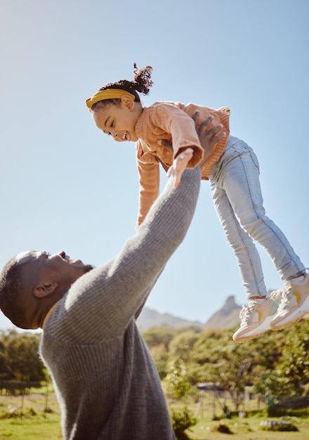 Pai levantando criança no ar no jardim do parque e natureza ao ar livre para se divertir e passar bons momentos juntos como família negra Pai jogando menina no céu enquanto brincava com amor, cuidado e relaxe