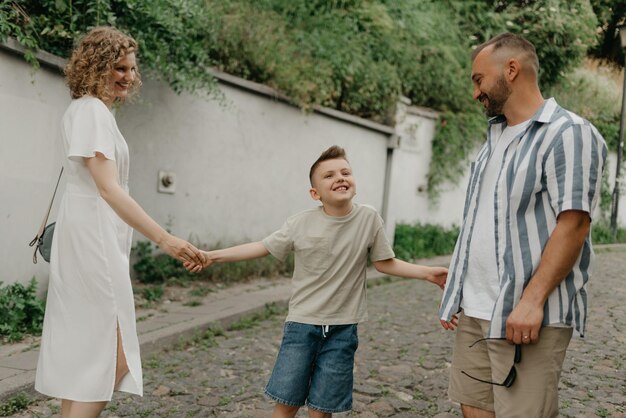 Foto pai mãe e filho estão de mãos dadas na rua de paralelepípedos verde