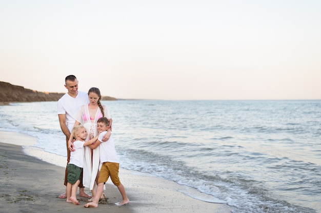 Pai, mãe grávida e dois filhos na costa do mar