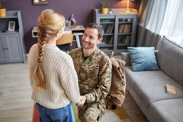 Pai militar voltando para casa e de mãos dadas com a filha