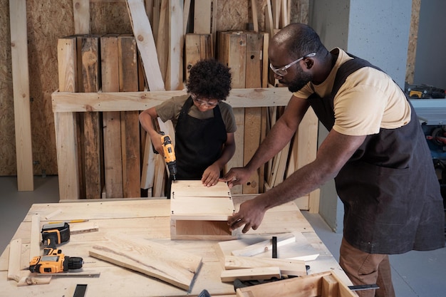 Pai negro ensinando carpintaria para filho