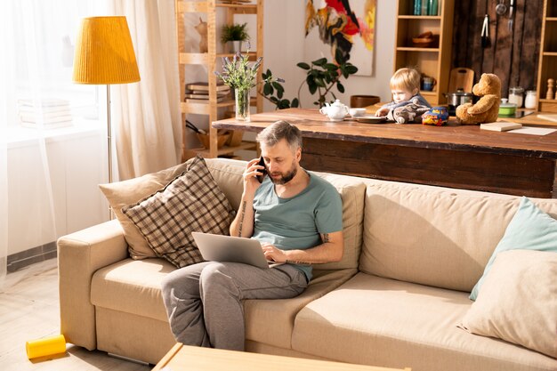 Pai ocupado trabalhando em casa enquanto filho sendo entediado