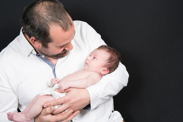 Pai olha para seu bebê em seus braços