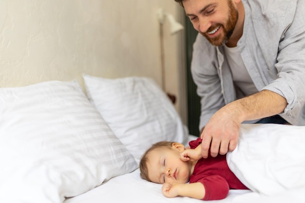 Pai olhando ternamente para seu bebê adormecido no interior do quarto da casa