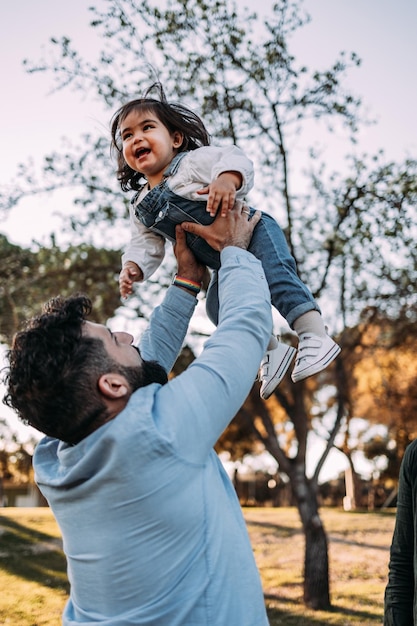 Foto pai orgulhoso joga sua filha no ar que ri alegremente