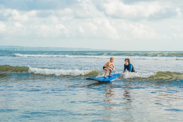 Pai ou instrutor ensinando seu filho de 4 anos a surfar no mar nas férias ou feriado. Viagens e esportes com conceito de crianças. Aula de surf para crianças