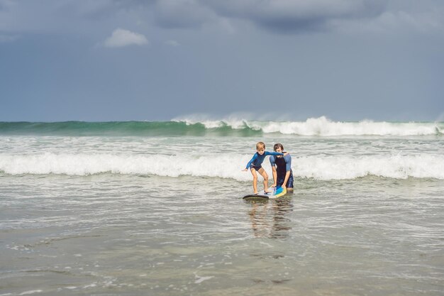 Pai ou instrutor ensinando seu filho de 5 anos a surfar no mar nas férias ou férias Viagens e esportes com conceito infantil Aula de surf para crianças