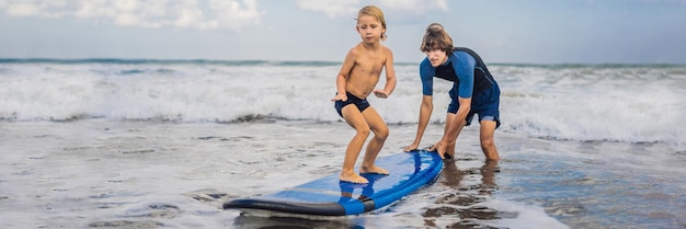 Pai ou instrutor ensinando seu filho de um ano a surfar no mar em férias ou viagens de férias