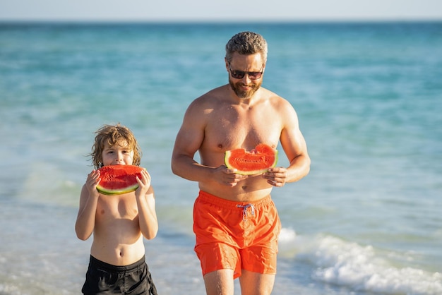 Pai pai e filho comendo melancia pai e filho nas férias de verão pai solteiro pai com filho filho na praia Pai amoroso e filho aproveitando o tempo de qualidade juntos nas férias de verão no mar