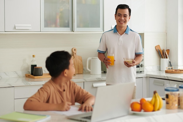 Pai preparando o café da manhã para o filho que estuda