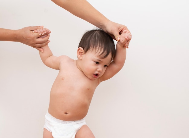 Pai segura as mãos do bebê enquanto ele tenta andar