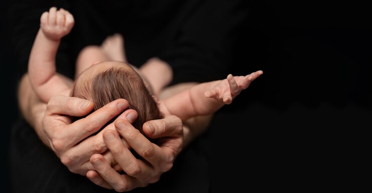 Pai segura filho recém-nascido nu em suas mãos em fundo preto