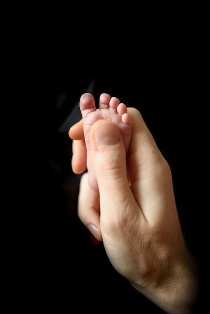 pai segura o pé minúsculo de seu filho recém-nascido.