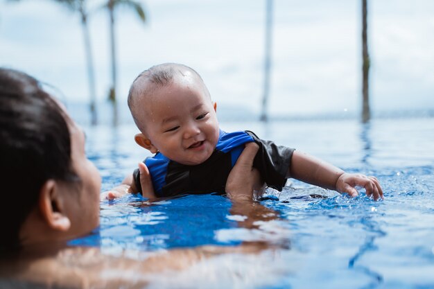 Pai segura seu bebê enquanto brincava na piscina