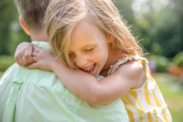 Foto pai segura sua filha em seus braços, garota feliz ri e abraça seu pai de perto família feliz