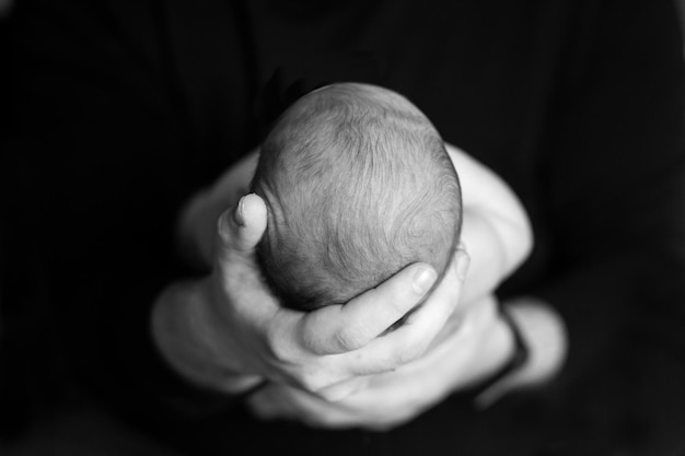 Pai segurando a cabeça de seu filho recém-nascido nas mãos O bebê nas mãos do pai Pais amorosos mão segurando um lindo bebê recém-nascido dormindo