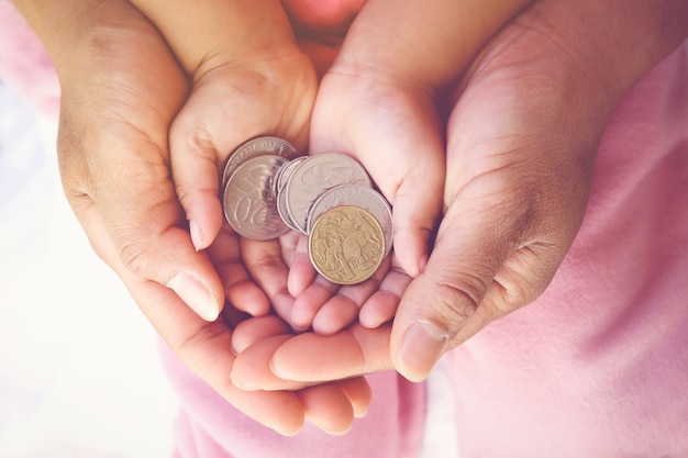 Pai segurando as mãos de criança com moedas de dinheiro, salvando o conceito