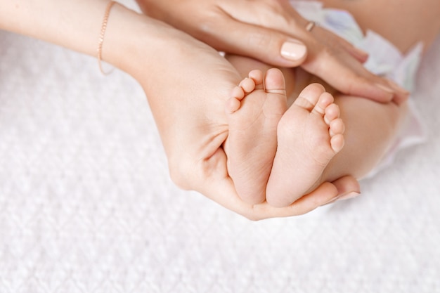 Pai segurando nas mãos pés do bebê recém-nascido. Os pés do bebê recém-nascido minúsculo no close up das mãos.