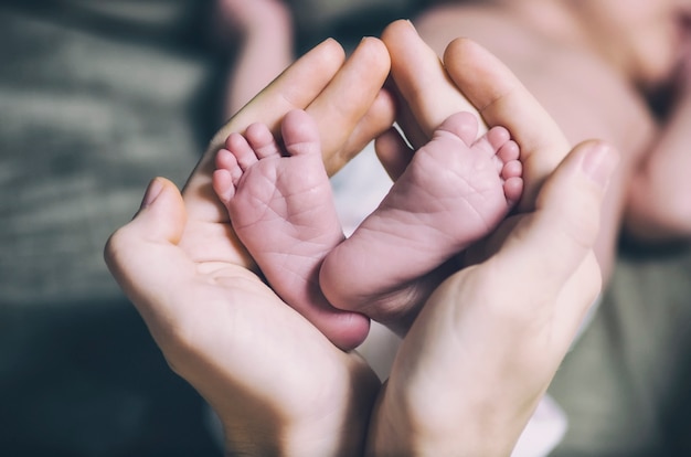 Pai segurando nas mãos pés do bebê recém-nascido.