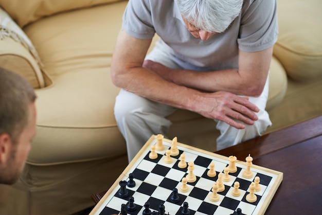 pai sênior ou jogando xadrez em casa para jogos ou competição com estratégia e resolução de problemas pai idoso acima e tabuleiro para desafio ou aprendizagem de habilidades de pensamento para a função cognitiva