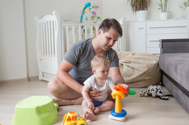 Pai sentado no chão com seu bebê brincando com brinquedos