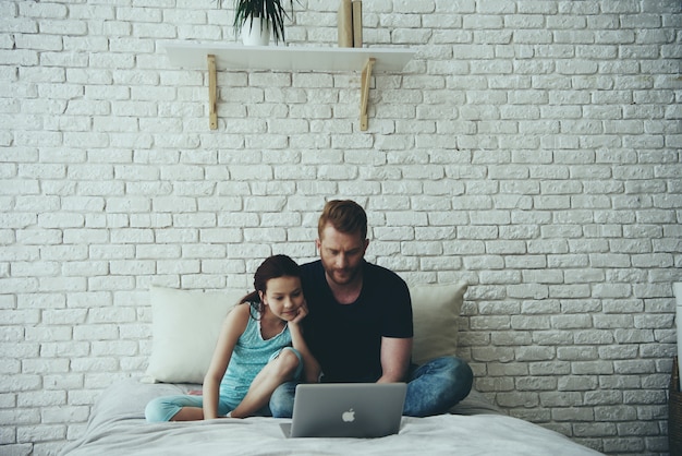 Pai solteiro e filha adolescente estão assistindo filme.