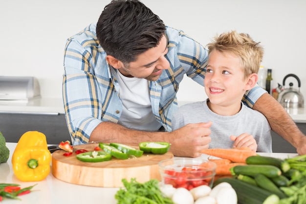 Pai sorrindo preparando vegetais com seu filho